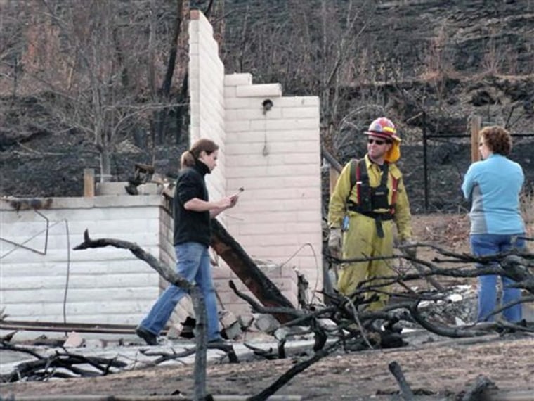 Austin Hardage, 23, left, returns Nov. 19 to the charred rubble that used to be the home where he and his wife, Sarah Hardage, 22, lived in an upscale community in the Sierra foothills in southwest Reno, Nev. before a wildfire destroyed that home and 31 others early Friday.